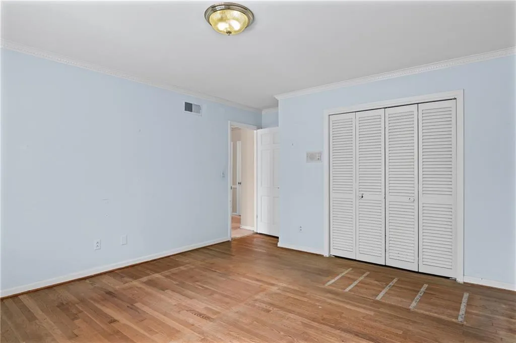 Unfurnished bedroom with ornamental molding, light wood finished floors, and a closet