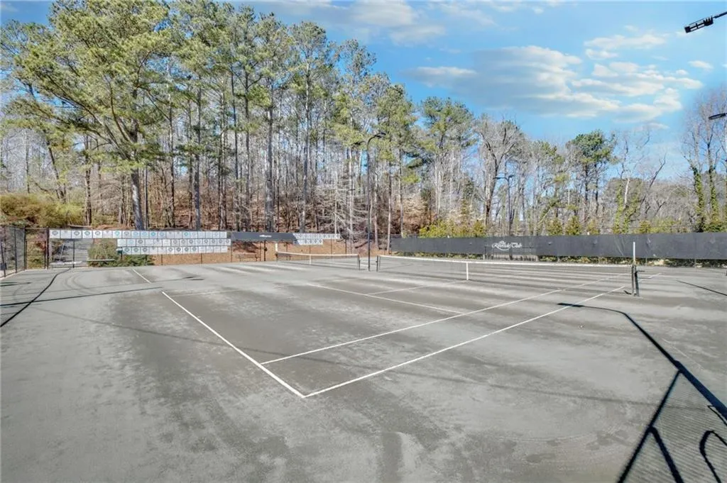 View of tennis court with view of wooded area