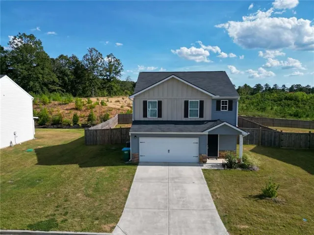 Two-story residence featuring a two-car garage, concrete driveway, and a fenced backyard