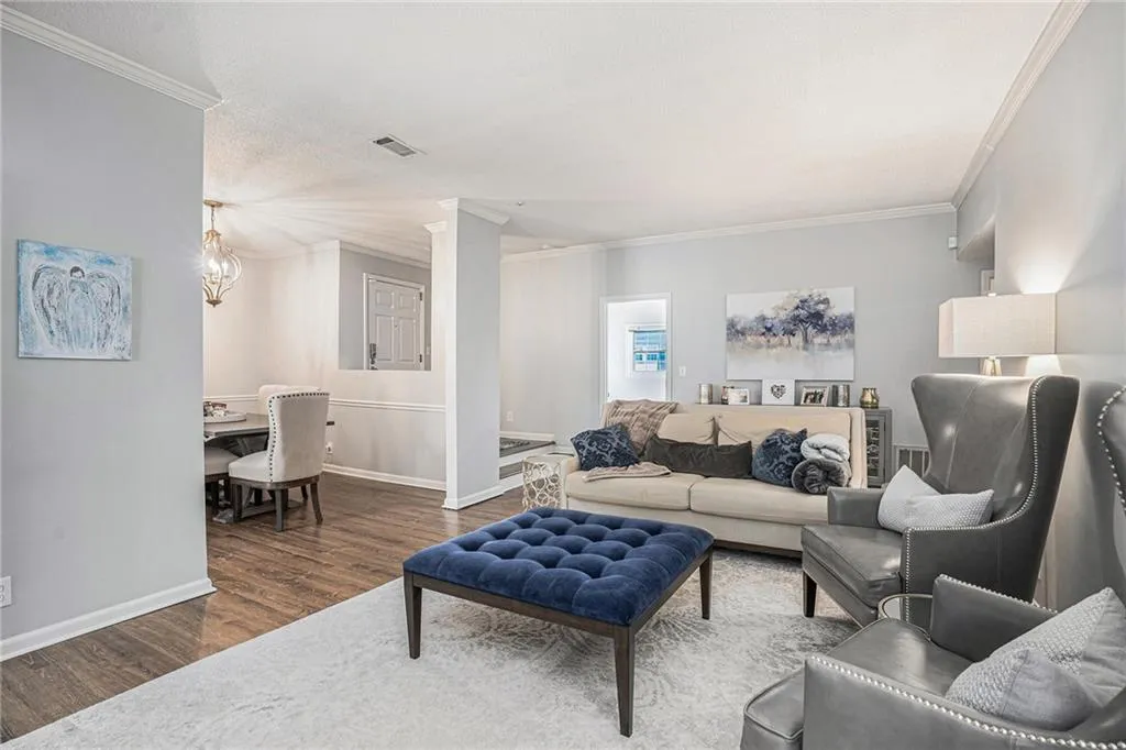 Living area featuring dark wood finished floors, crown molding, baseboards, and ornate columns
