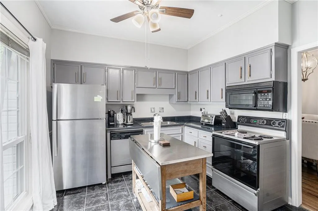 Kitchen with appliances with stainless steel finishes, gray cabinetry, a sink, ceiling fan, and crown molding