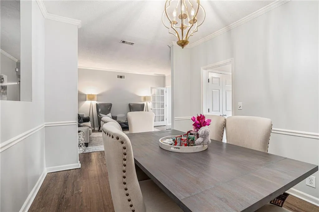 Dining area with crown molding, wood finished floors, baseboards, and a chandelier