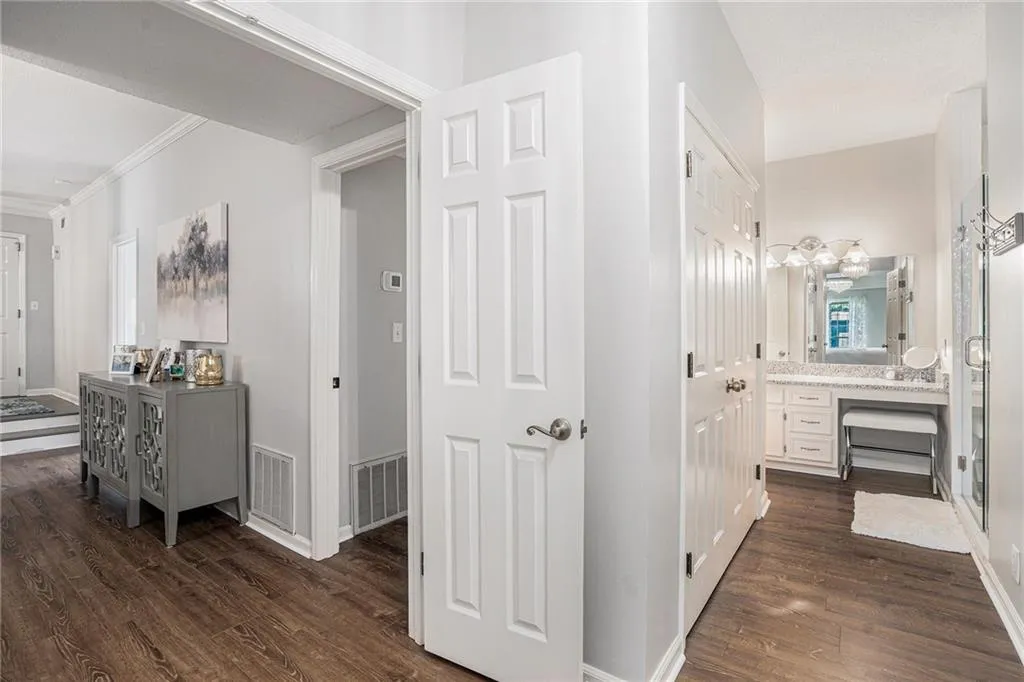 Hall with dark wood-style flooring, ornamental molding, and baseboards