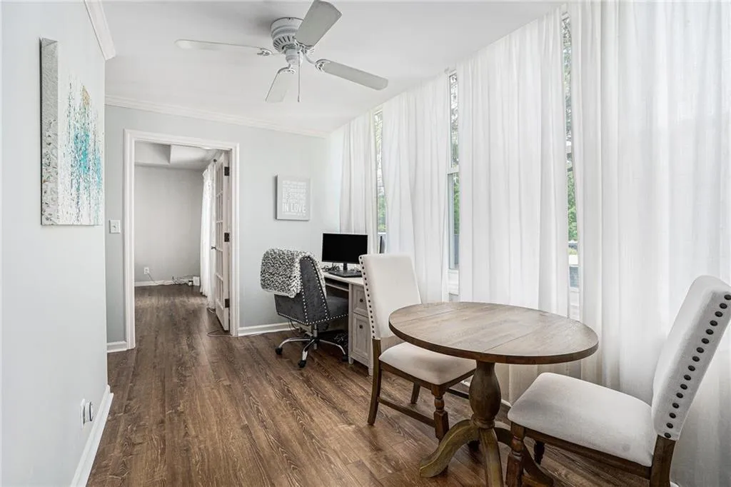 Office space featuring dark wood-type flooring, baseboards, crown molding, and a ceiling fan