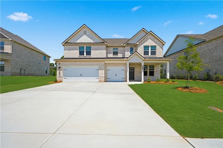 Two-story residence featuring light brick masonry, a covered entry porch with columns, a two-car garage with individual doors, gabled rooflines, and a concrete driveway