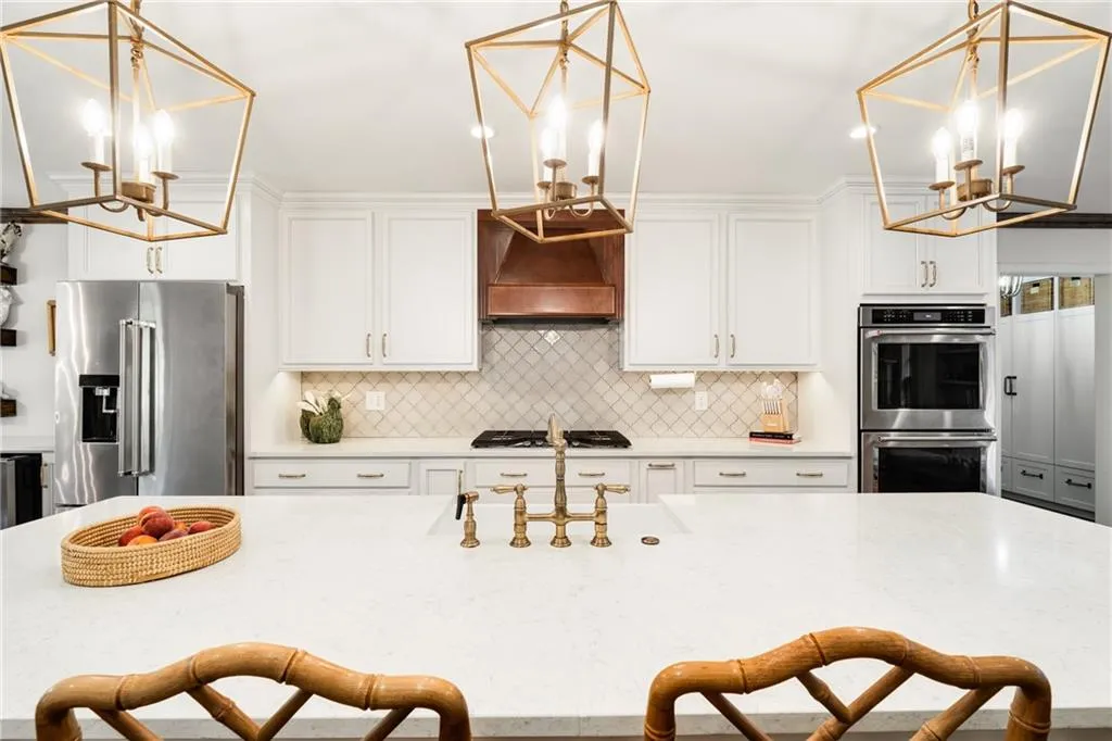KITCHEN ISLAND SEATING | VIEW OF CUSTOM VENT HOOD | DOUBLE OVENS | NEUTRAL TILE BACKSPLASH