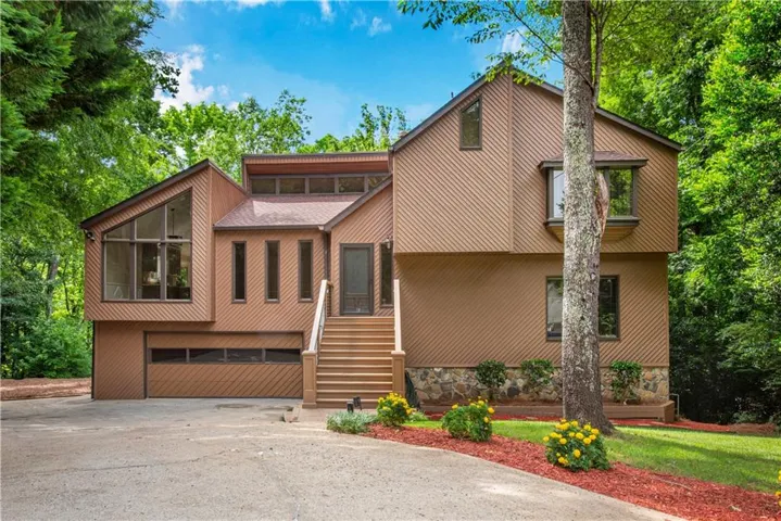Contemporary exterior with angled rooflines, integrated two-car garage, stone base, and prominent entry staircase