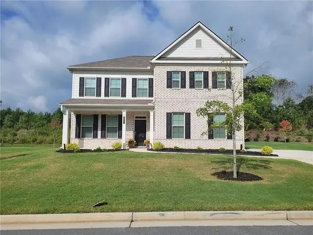 View of front of property with brick siding, covered porch, and a front lawn