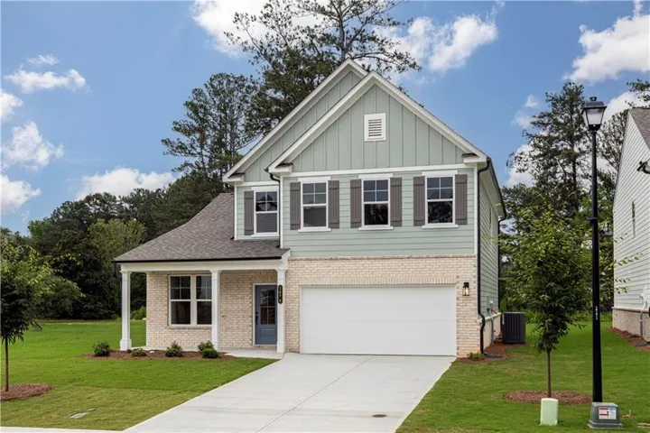 Two-story residence featuring a mixed-material facade, covered front porch, attached garage, and a concrete driveway