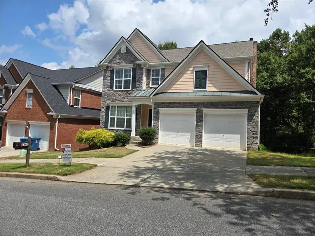Two-story residence featuring a stone and siding exterior, dual garage doors, and a concrete driveway