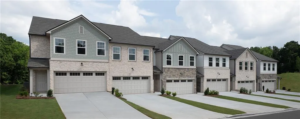 Contemporary townhome-style residences featuring brick and siding exteriors, two-car garages, and concrete driveways
