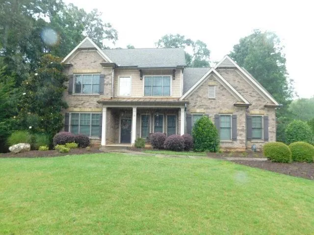 Brick and siding exterior featuring a covered front porch, gabled rooflines, and dark window shutters