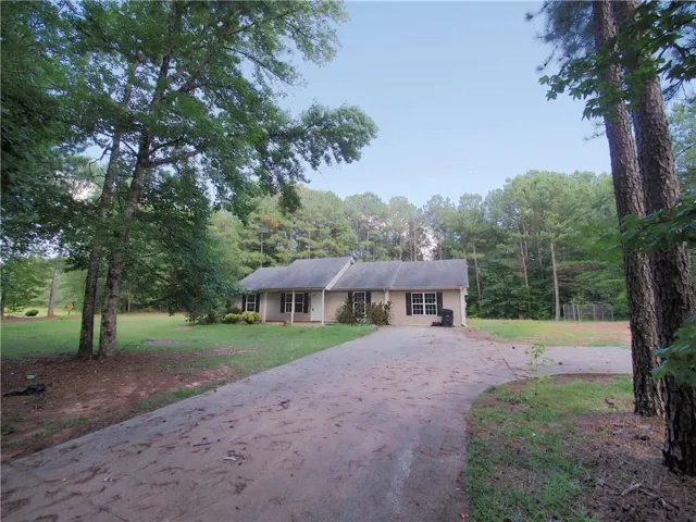 Ranch-style residence featuring a light-toned exterior, gabled roofline, and white-framed windows