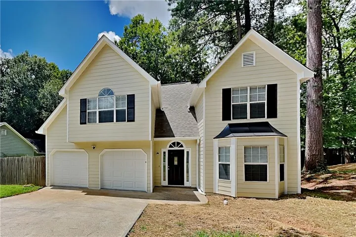 Two-story exterior with light-colored siding, a two-car garage, and a prominent bay window