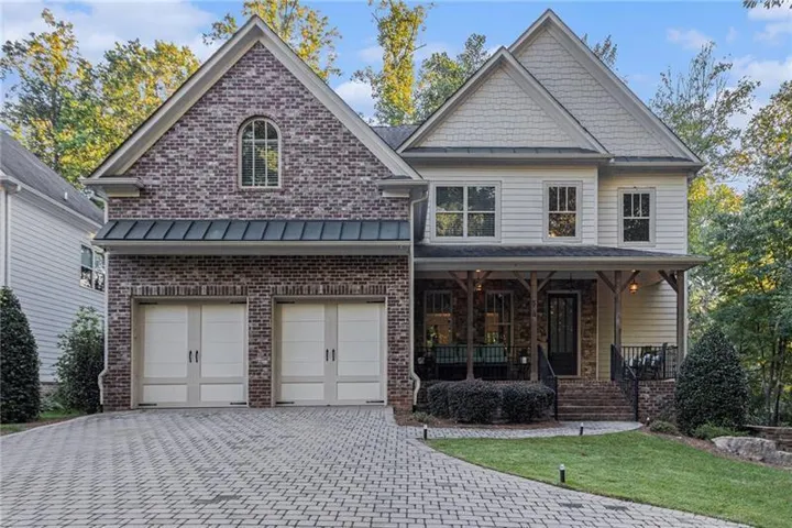 View of front of property featuring brick siding, a porch, a standing seam roof, and driveway