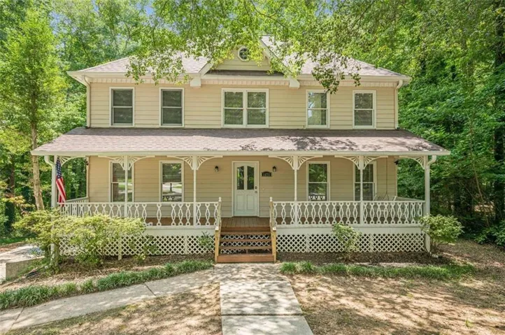 Two-story residence featuring a full-width front porch with decorative railing and columns, wood siding, and multiple double-hung windows
