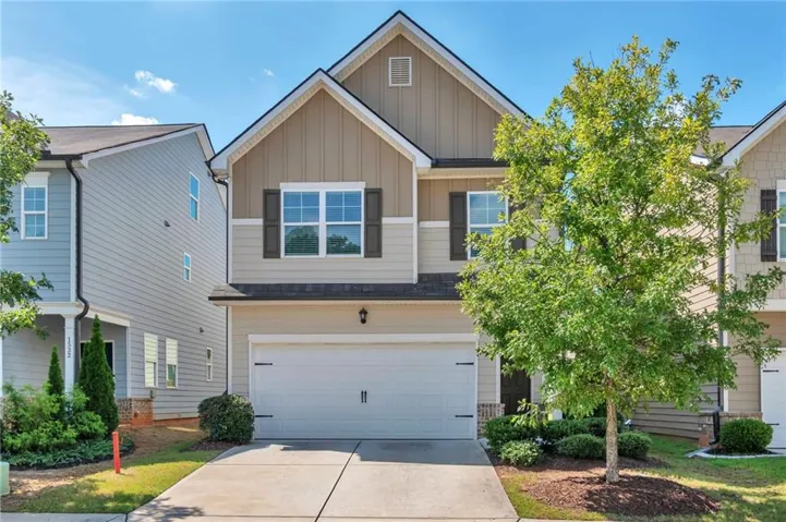 Two-story facade with mixed siding, an integrated garage, and a concrete driveway