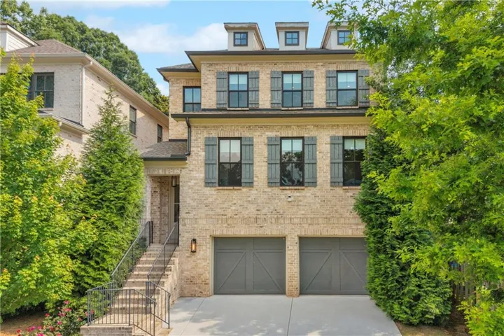 Three-story brick exterior featuring dormer windows, decorative window shutters, and a covered entry