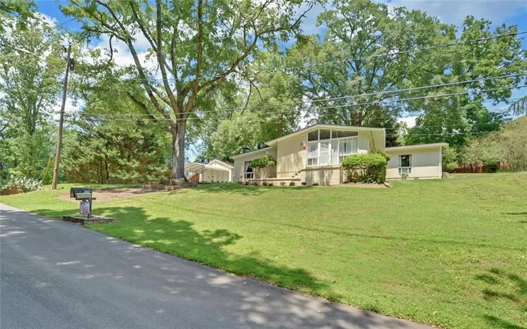 Mid-century modern residence featuring a light-colored exterior with a screened porch and a carport