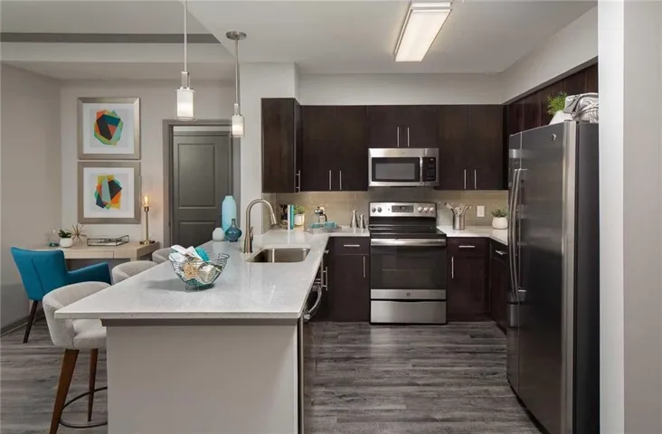 Kitchen with sink, appliances with stainless steel finishes, dark wood-type flooring, a breakfast bar area, and kitchen peninsula