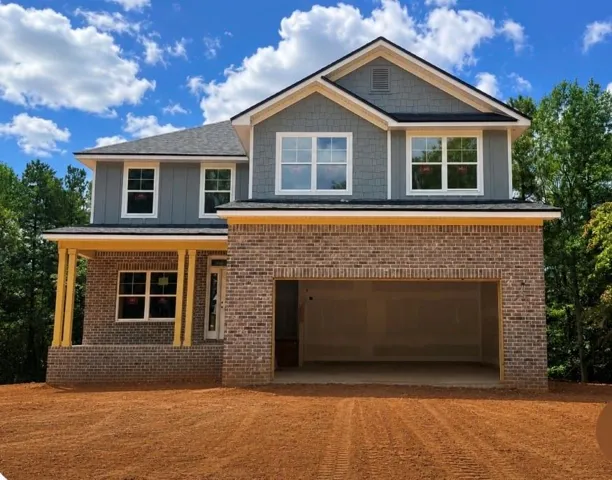 Two-story residence featuring brick and siding exterior, multi-pane windows, covered front porch, and an integrated two-car front entry garage