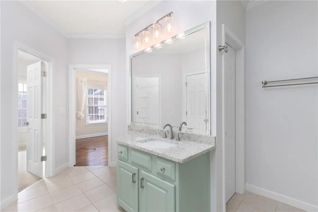 Bathroom with tile patterned floors, vanity, and ornamental molding