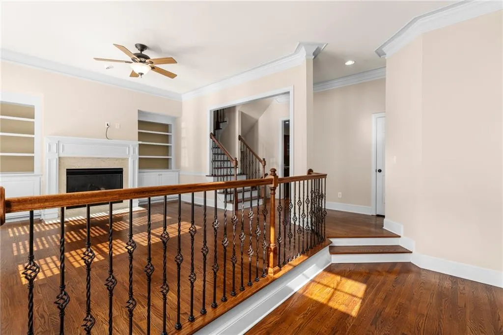 Hallway with baseboards, wood finished floors, built in features, and crown molding