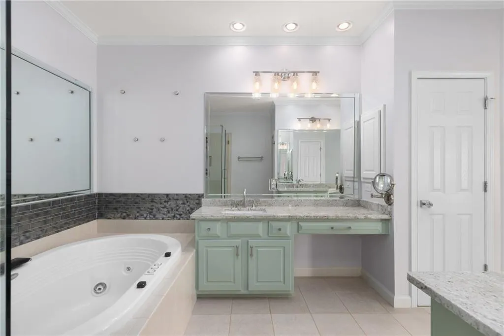 Bathroom featuring a tub with jets, tile patterned flooring, ornamental molding, vanity, and a stall shower