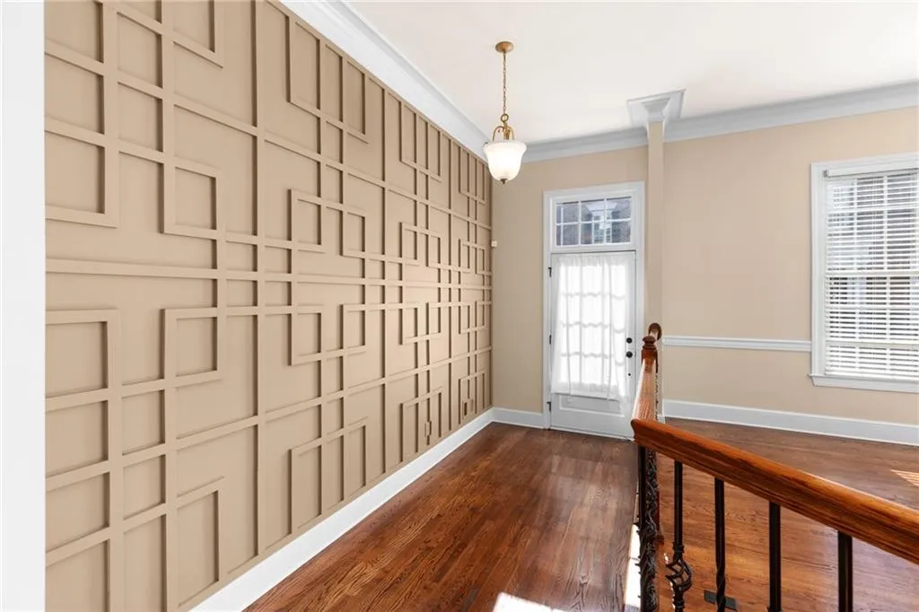 Entryway with ornamental molding, dark wood finished floors, and baseboards