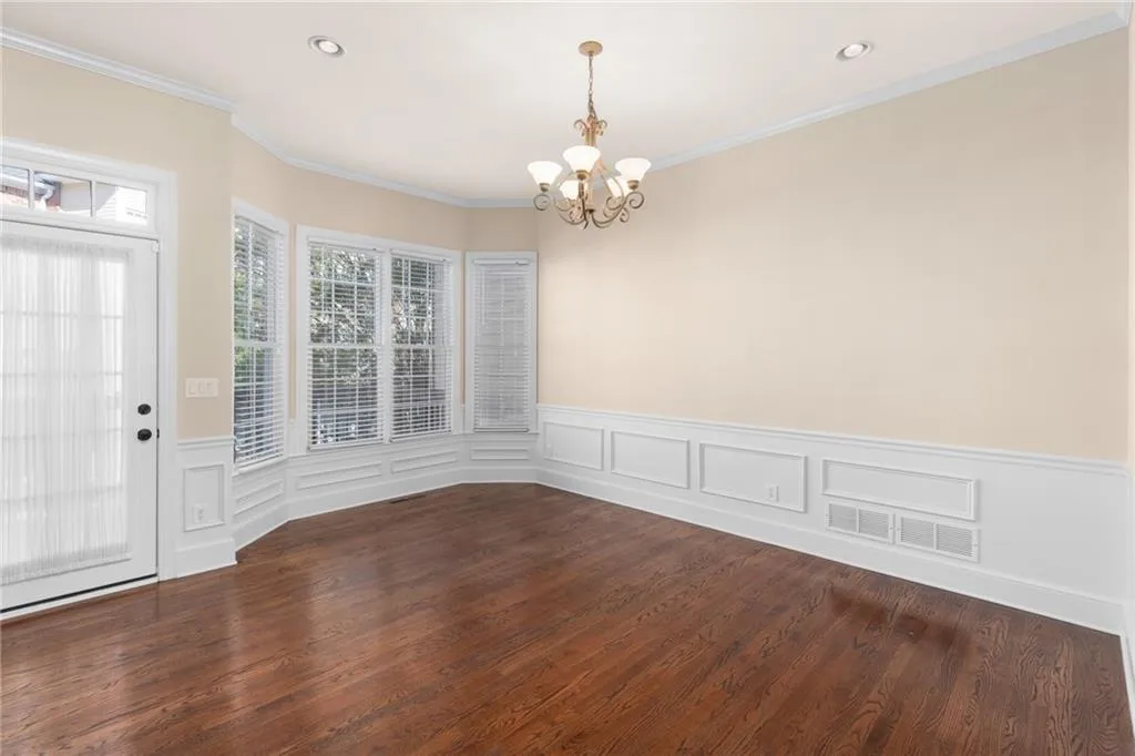 Unfurnished dining area with an inviting chandelier, visible vents, a wainscoted wall, and ornamental molding