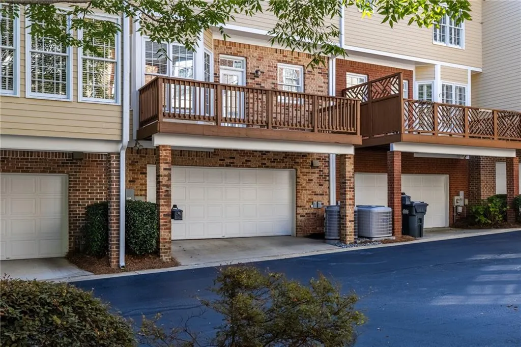 Back of property with central AC, a balcony, brick siding, and a garage