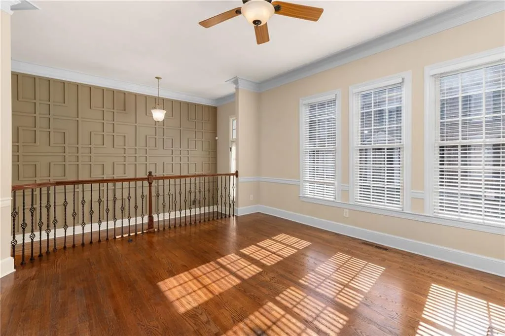 Spare room with wood finished floors, ceiling fan, baseboards, visible vents, and crown molding
