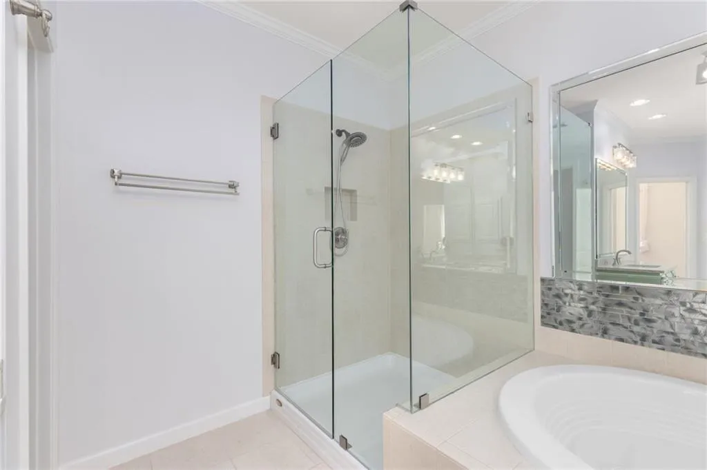Full bath with a stall shower, ornamental molding, and a bath