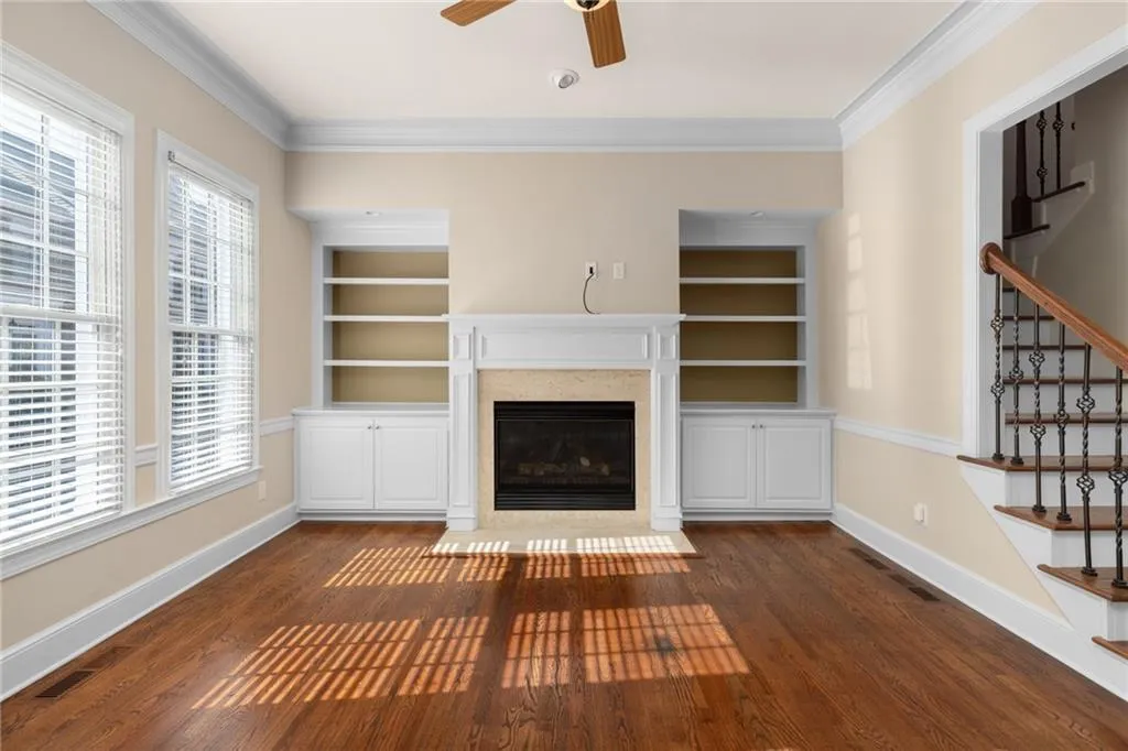 Unfurnished living room with a ceiling fan, stairs, dark wood-style flooring, and a fireplace
