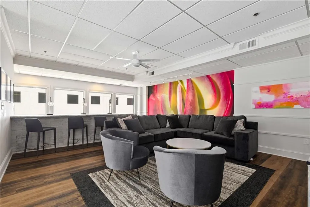 Living area with ceiling fan, a drop ceiling, and dark wood-style flooring