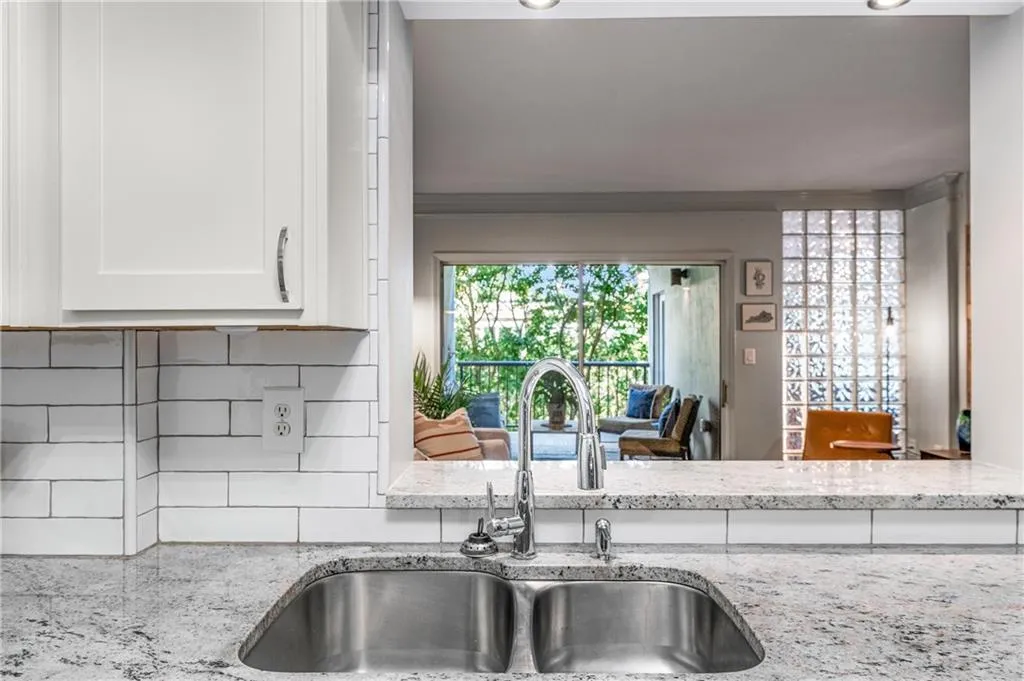 Kitchen featuring light stone countertops, white cabinets, tasteful backsplash, and ornamental molding