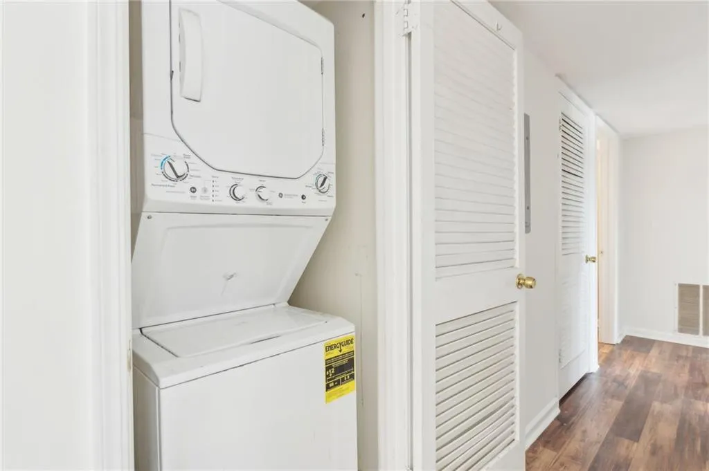 Laundry area with stacked washing machine and dryer and dark wood finished floors