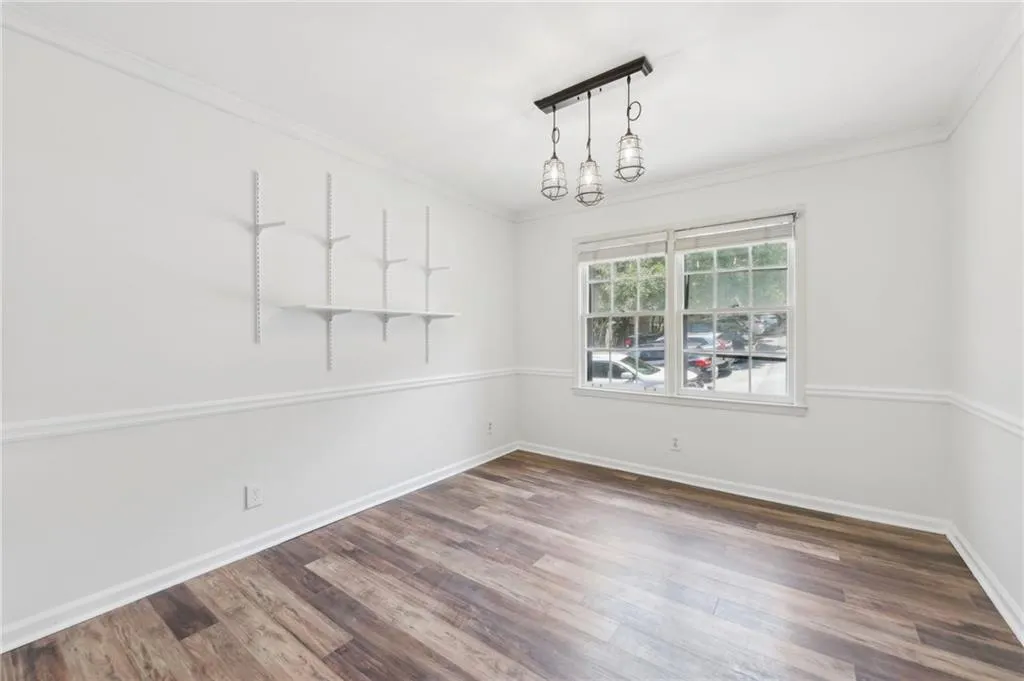Spare room featuring wood finished floors, ornamental molding, and a chandelier