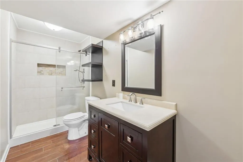 Bathroom with wood finished floors, a shower stall, and vanity