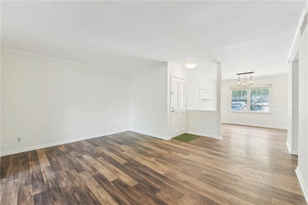 Empty room featuring dark wood finished floors, a chandelier, and ornamental molding