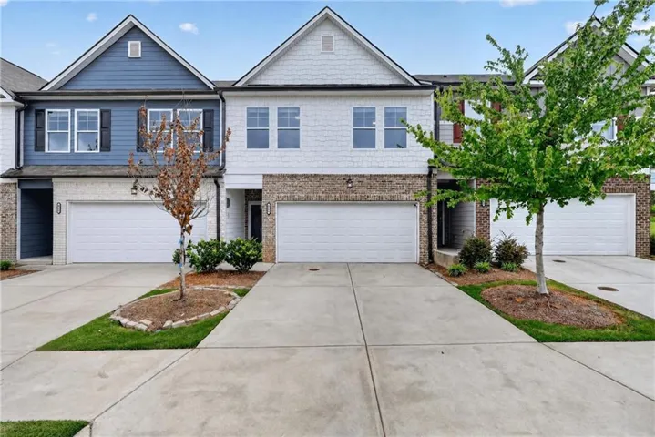 Townhome exterior with a two-car garage, brick and siding facade, and landscaped entries