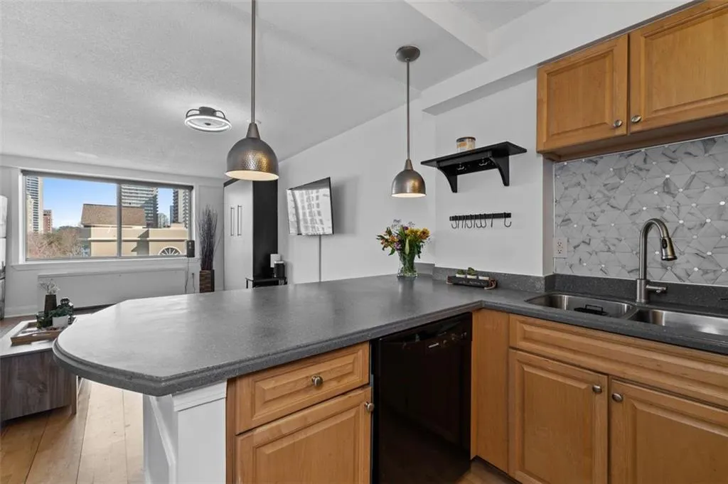 Kitchen with a sink, dark countertops, dishwasher, and a peninsula