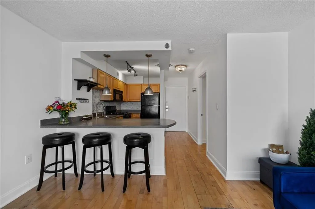 Kitchen with light wood-type flooring, black appliances, tasteful backsplash, a peninsula, and a breakfast bar area