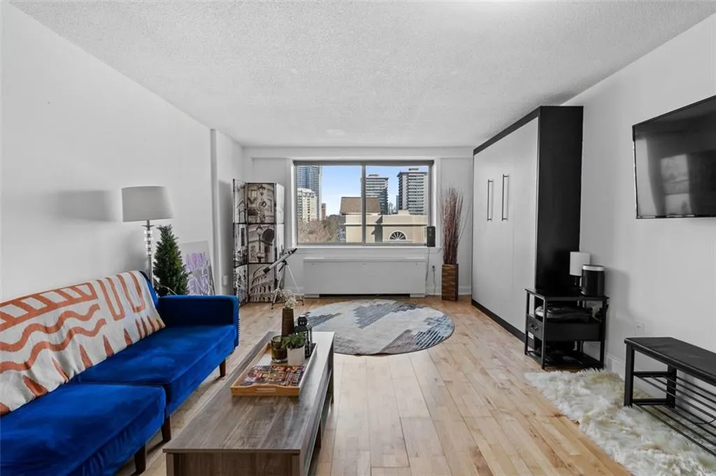 Living area with baseboards, a textured ceiling, and light wood-style flooring