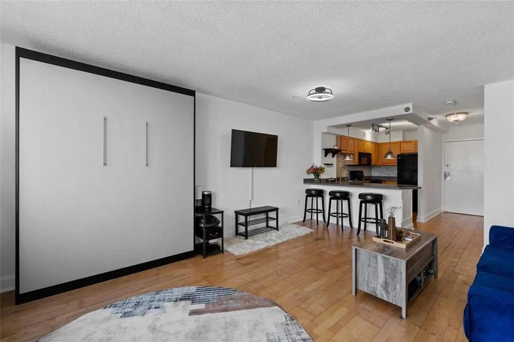 Living area with baseboards, a textured ceiling, and light wood finished floors