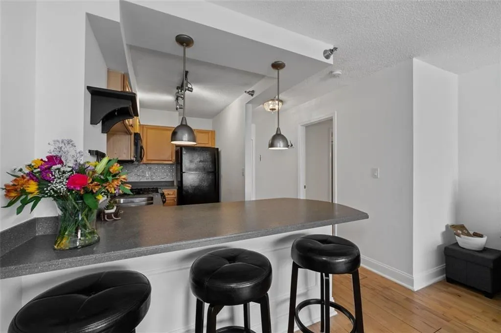 Kitchen with light wood-type flooring, black appliances, tasteful backsplash, dark countertops, and a peninsula