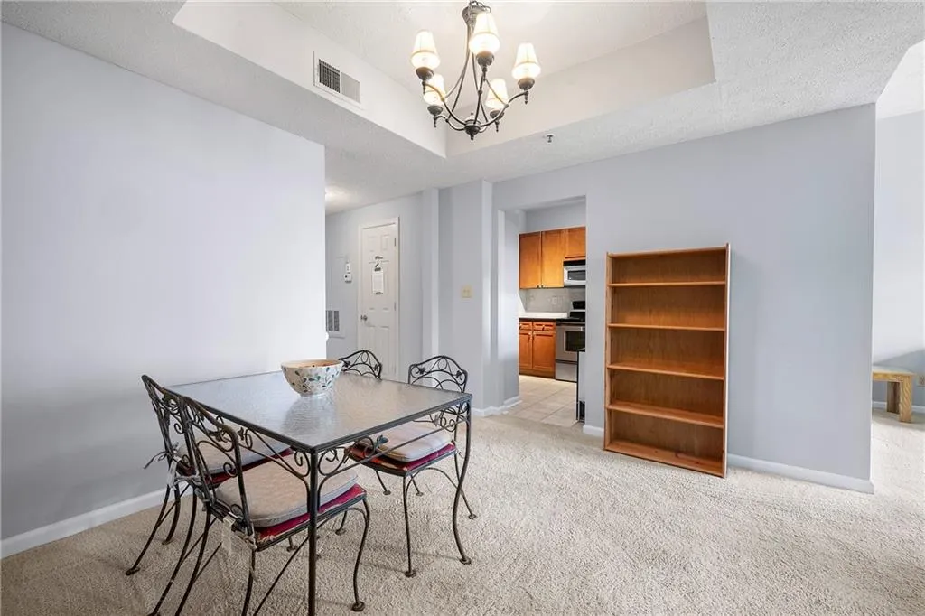 Dining space with a chandelier, light colored carpet, and a textured ceiling