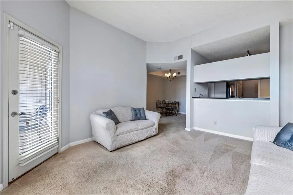 Carpeted living area with a chandelier, lofted ceiling, and a textured ceiling