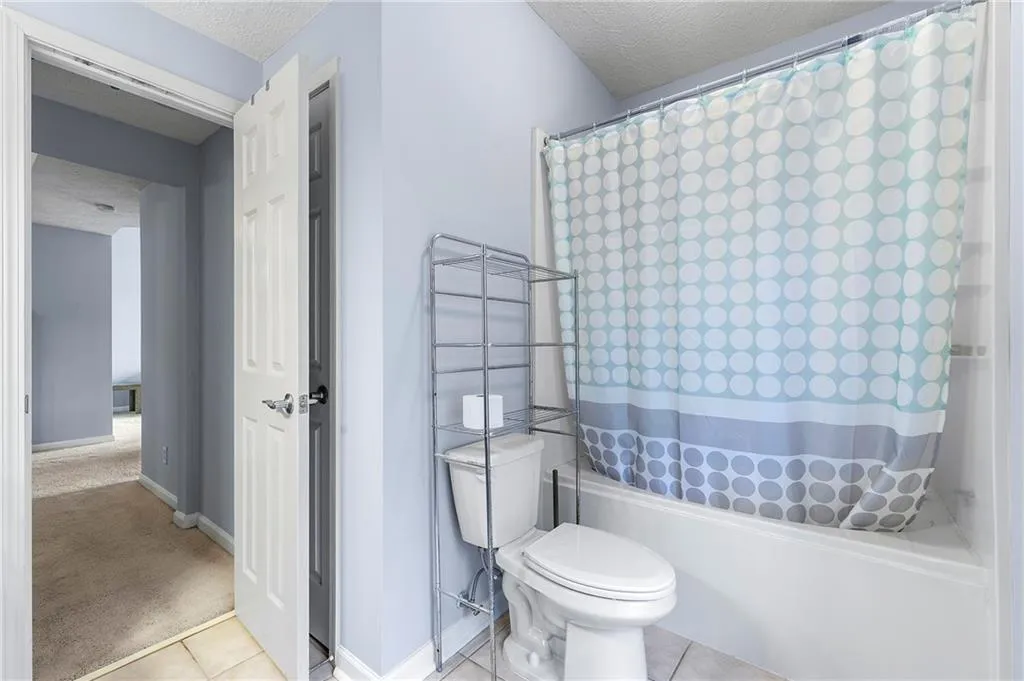 Full bathroom with a textured ceiling, tile patterned floors, and shower / bath combination with curtain