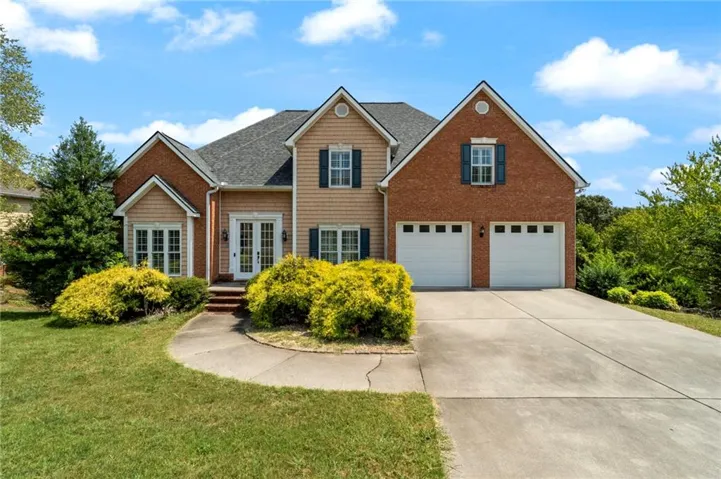 View of front facade featuring french doors, a garage, and a front lawn